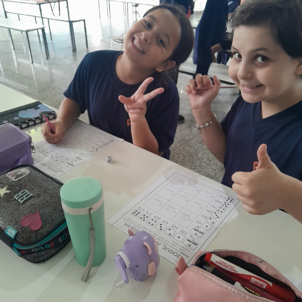 Duas alunas sorrindo durante atividade escrita em sala de aula