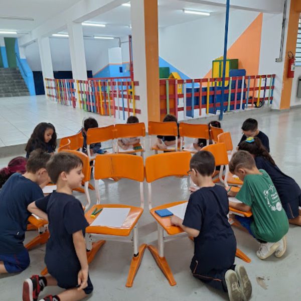 Alunos em atividade em mesas coletivas na área de convivência do Colégio Pentágono