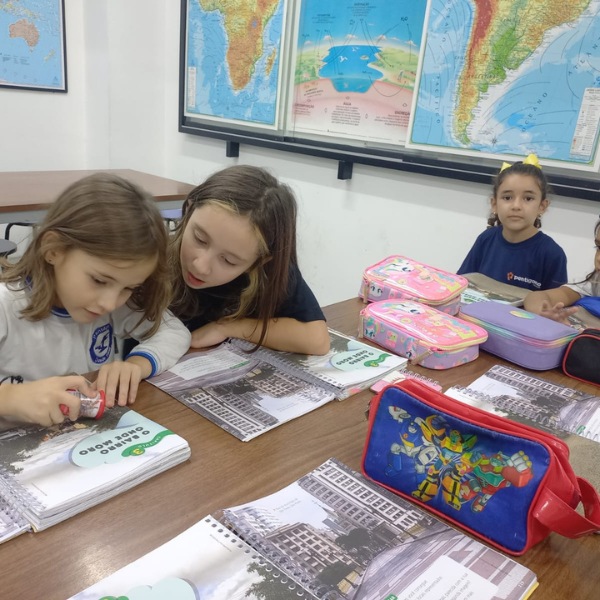 Alunas dos Anos Iniciais em aula de Geografia com mapas na parede