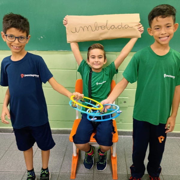 Alunos apresentando projeto com cartaz e bambolê na sala de aula