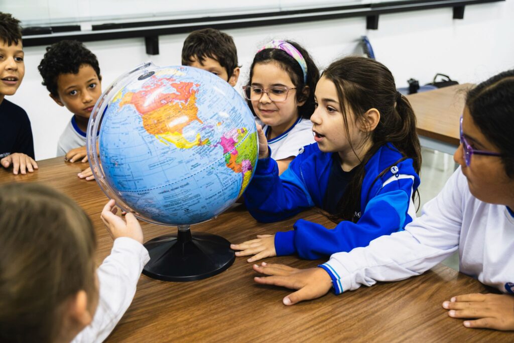 Alunos observando globo terrestre em aula no Colégio Pentágono