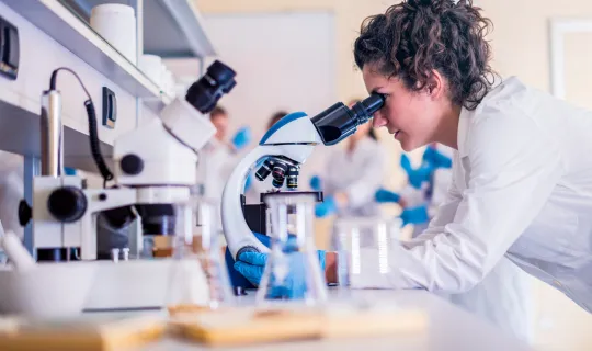 Profissional de jaleco utilizando microscópio em laboratório