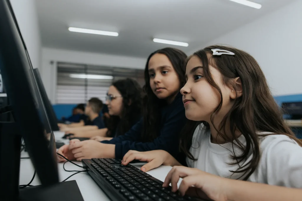 Alunas dos Anos Iniciais usando computadores no laboratório de informática