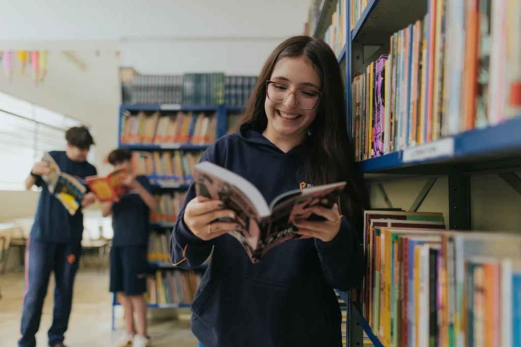 Aluna do Colégio Pentágono lendo livro na biblioteca