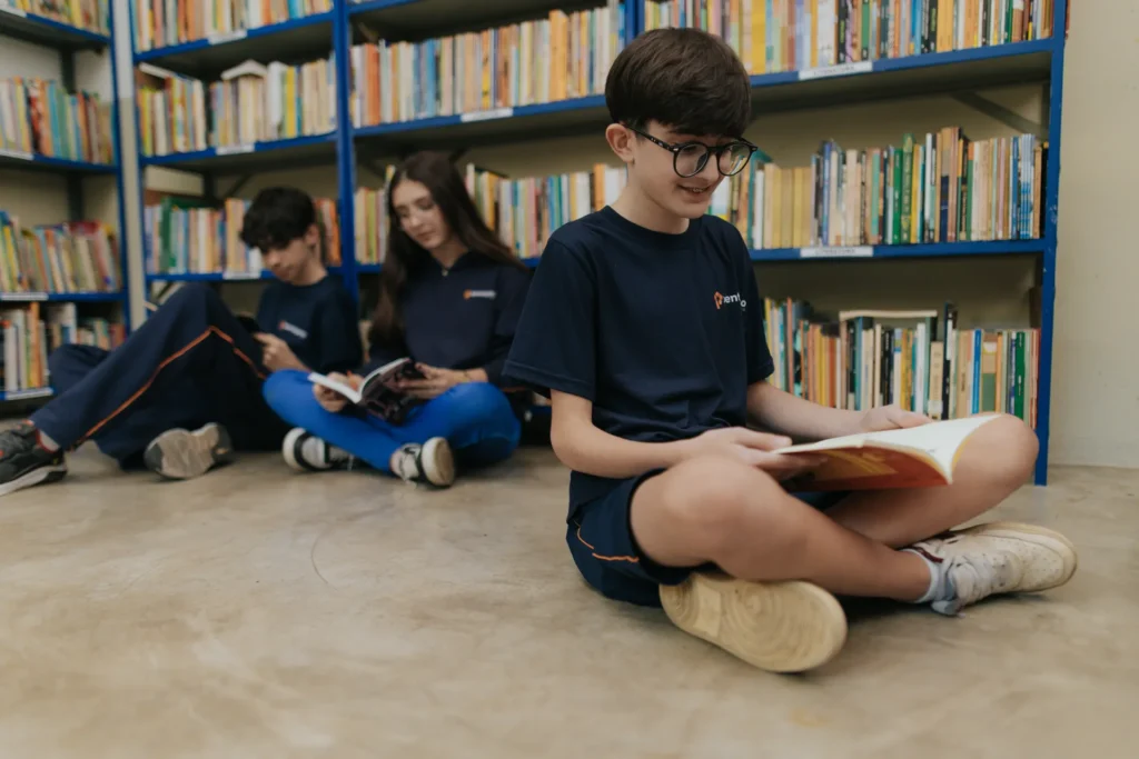 Alunos dos Anos Finais lendo sentados no chão da biblioteca