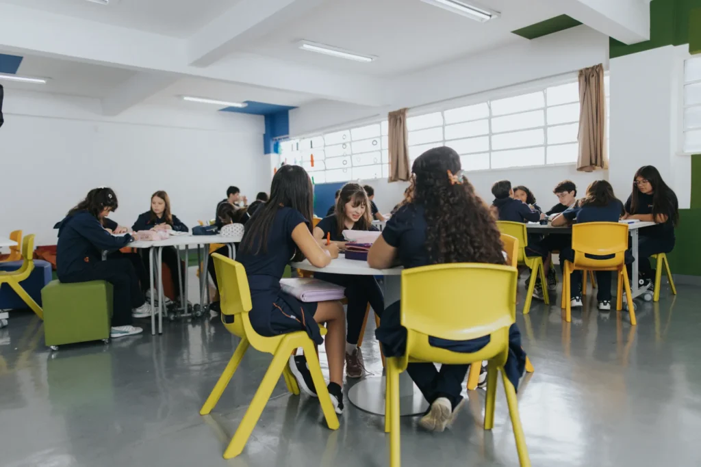 Sala de aula do Colégio Pentágono com alunos em mesas de trabalho em grupo